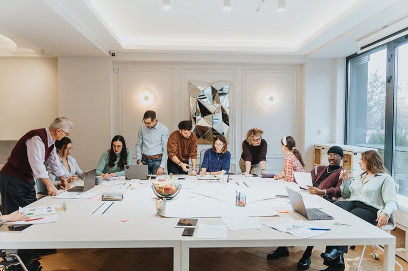 A team of people collaborating at a planning meeting around a white table